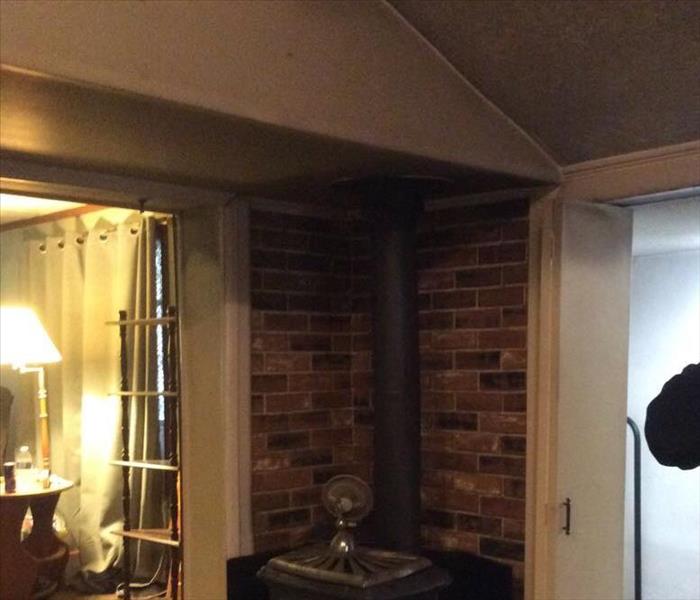 A basement picture of a brick wall and a fire place, which has caused smoke damage. 