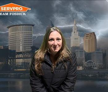 Brownish-blonde woman smiling in a black winter jacket in front of a stormy Cleveland background